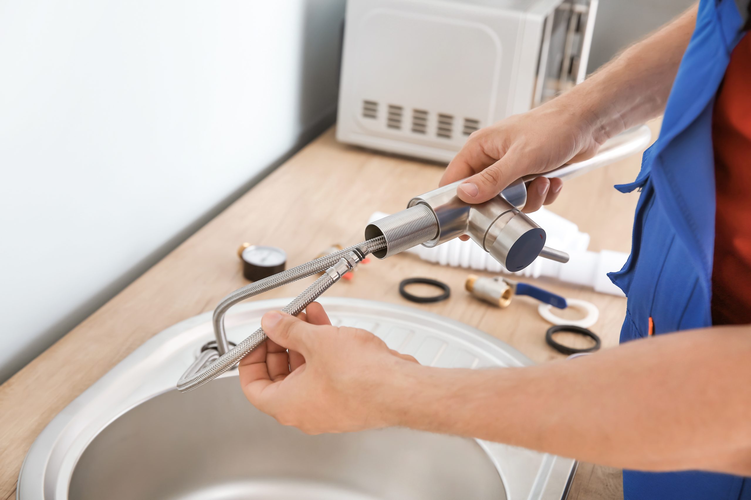 Plumber installing sink in kitchen